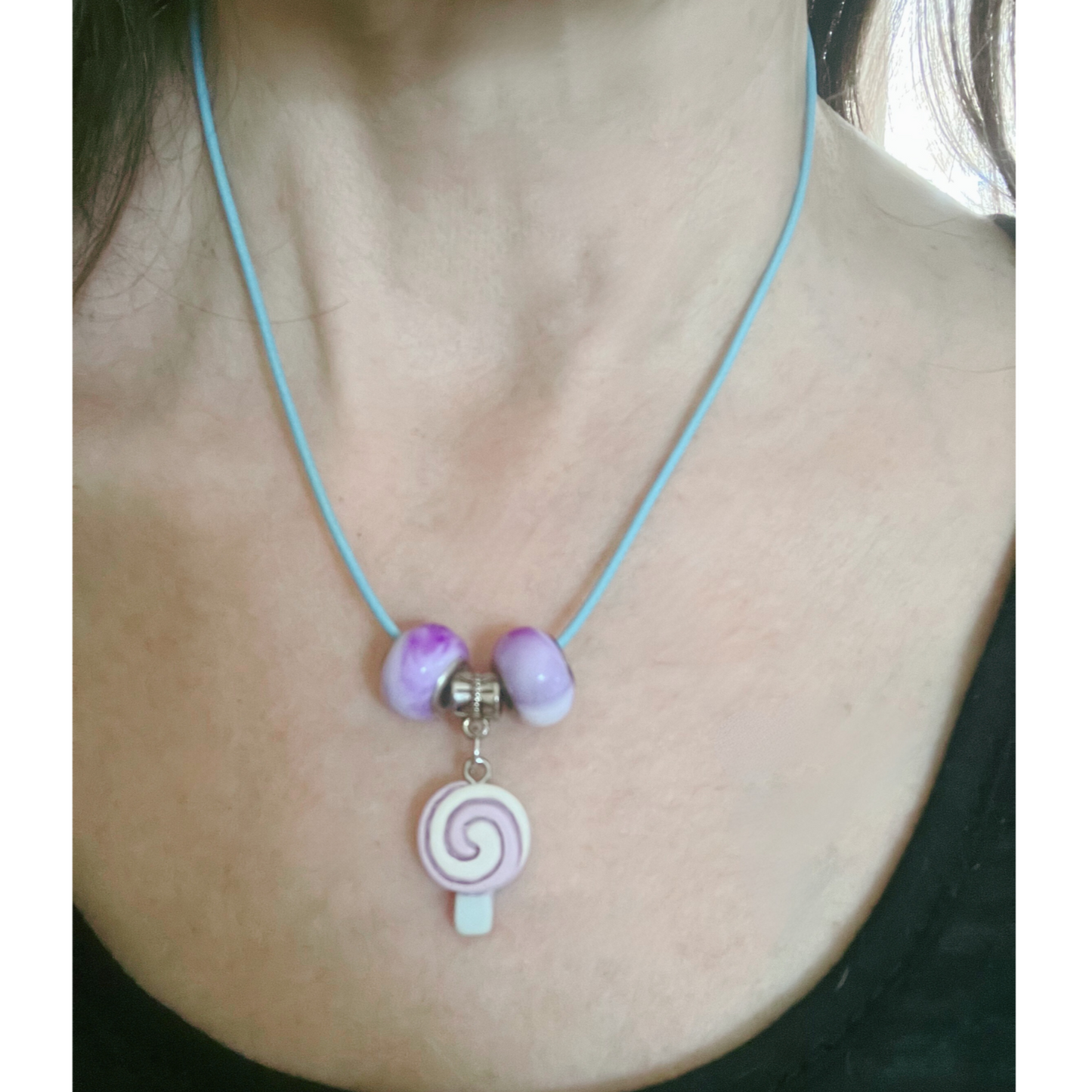 Blue cord necklace with purple beads and candy pendant.