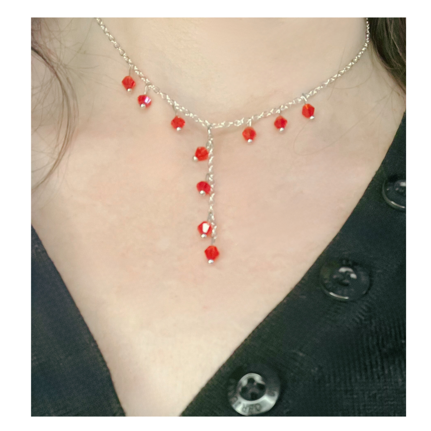 Silver necklace with red beads.
Colar prateado com missangas vermelhas.