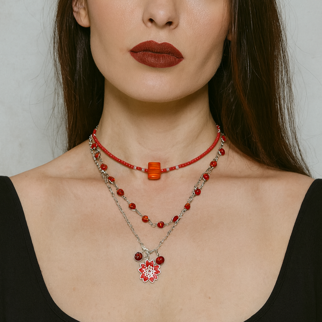 Three red beaded necklace with a silver chain and floral pendant.