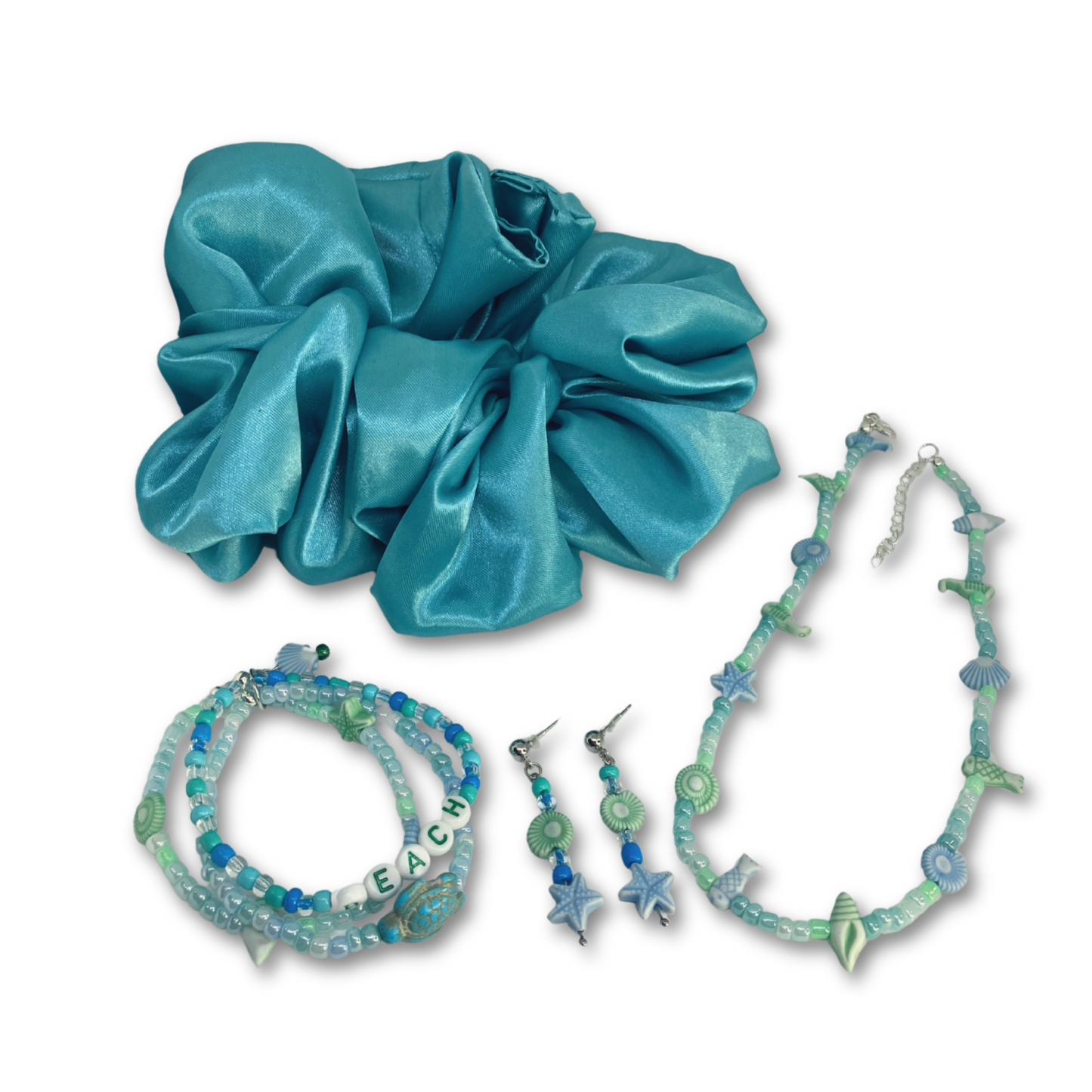 Serene Ocean Bliss gift set consists of turquoise satin hair scrunchie, beach beads necklace with matching earrings and three bracelets.
Elástico de cabelo em cetim turquesa, colar de contas de praia com brincos a condizer e três pulseiras.