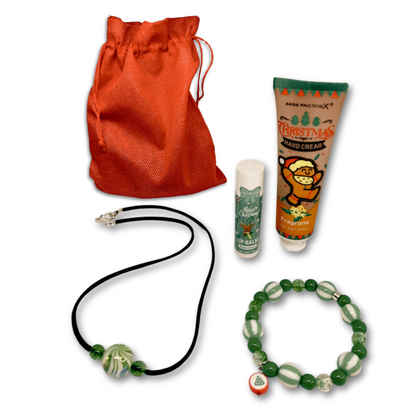 A Christmas gift of black suede necklace, green bracelet, lip balm and hand cream. Packaged in red gift bag.