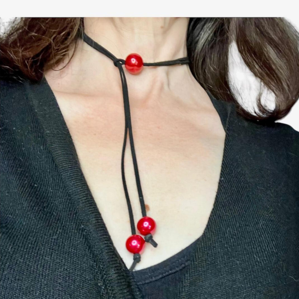  Black suede cord necklace with red beads.
Cordão de camurça preta com missangas vermelhas.