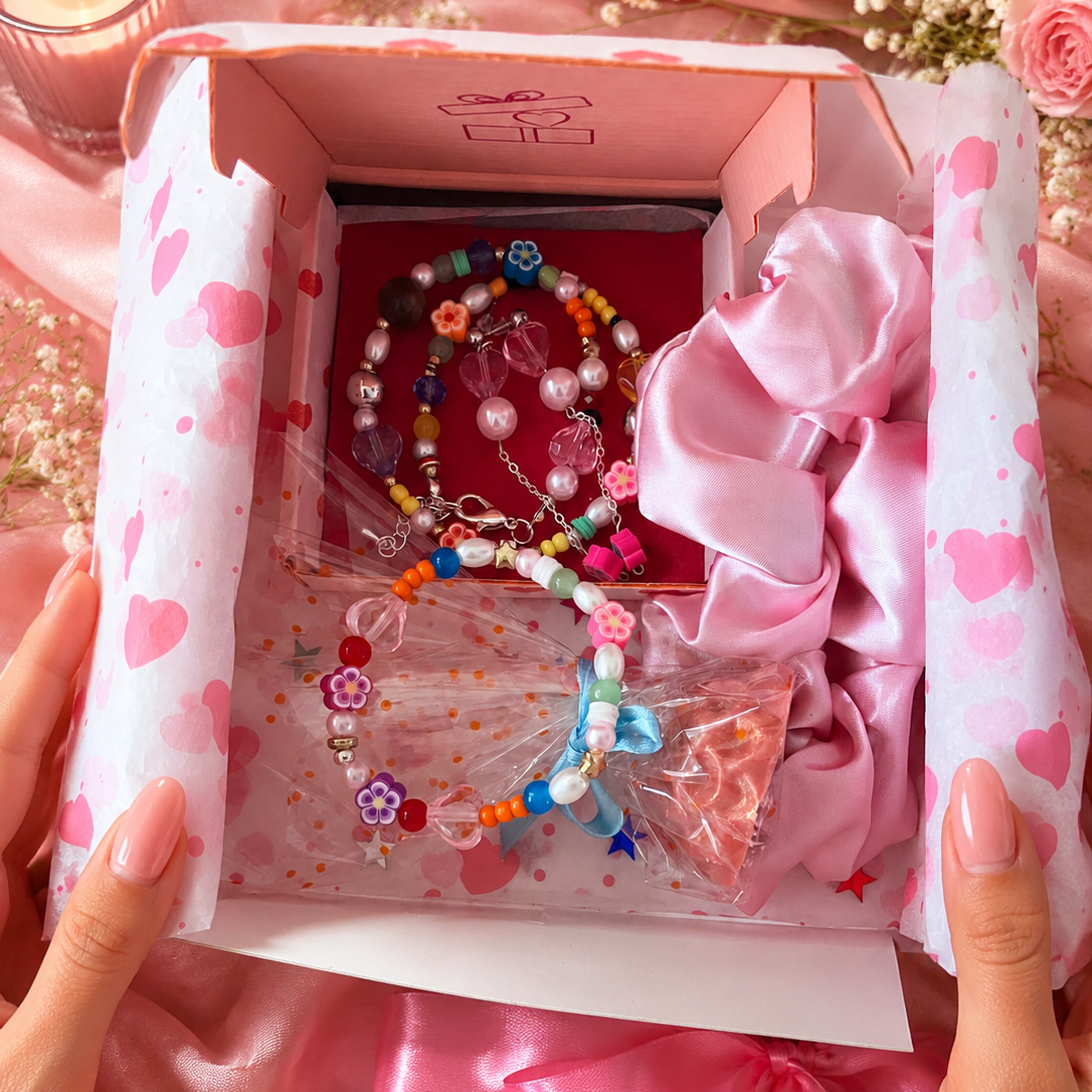 Set of colorful jewelry including a bracelet, earrings, and hair tie in a gift box with a pink ribbon.