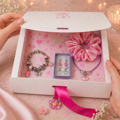 Gift set with bracelet, earrings, and scrunchie in a decorative box on a pink background.
