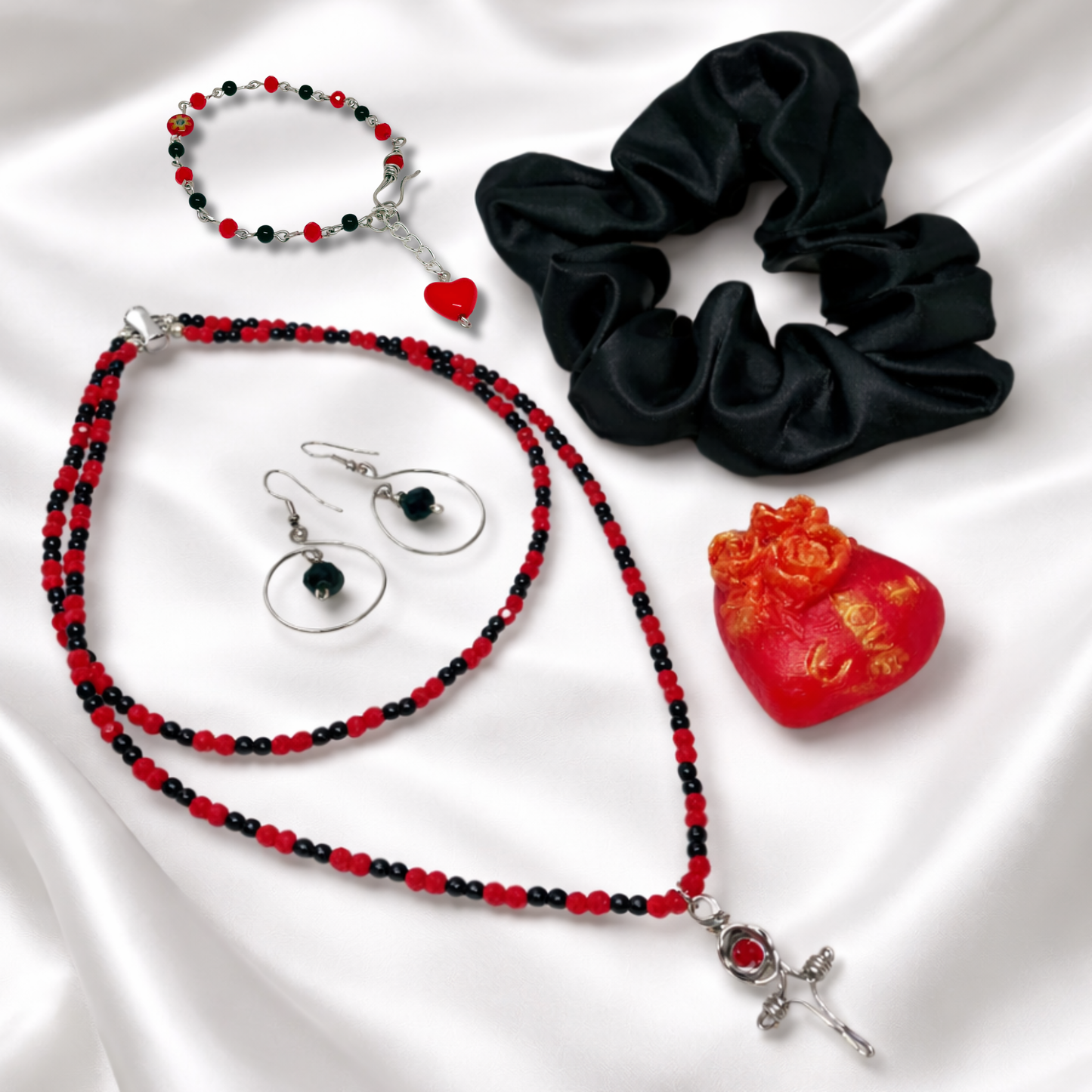 This set includes, red and black bead necklace with cross, earrings, bracelet beeswax candle and black satin scrunchie.