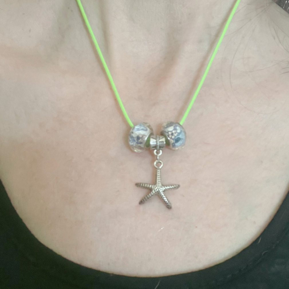 Green cord necklace with glass blue beads and silver star pendant.
