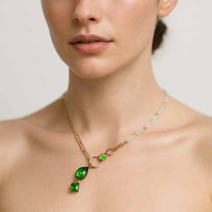 Necklace with beads and gold chain with green pendant worn.
