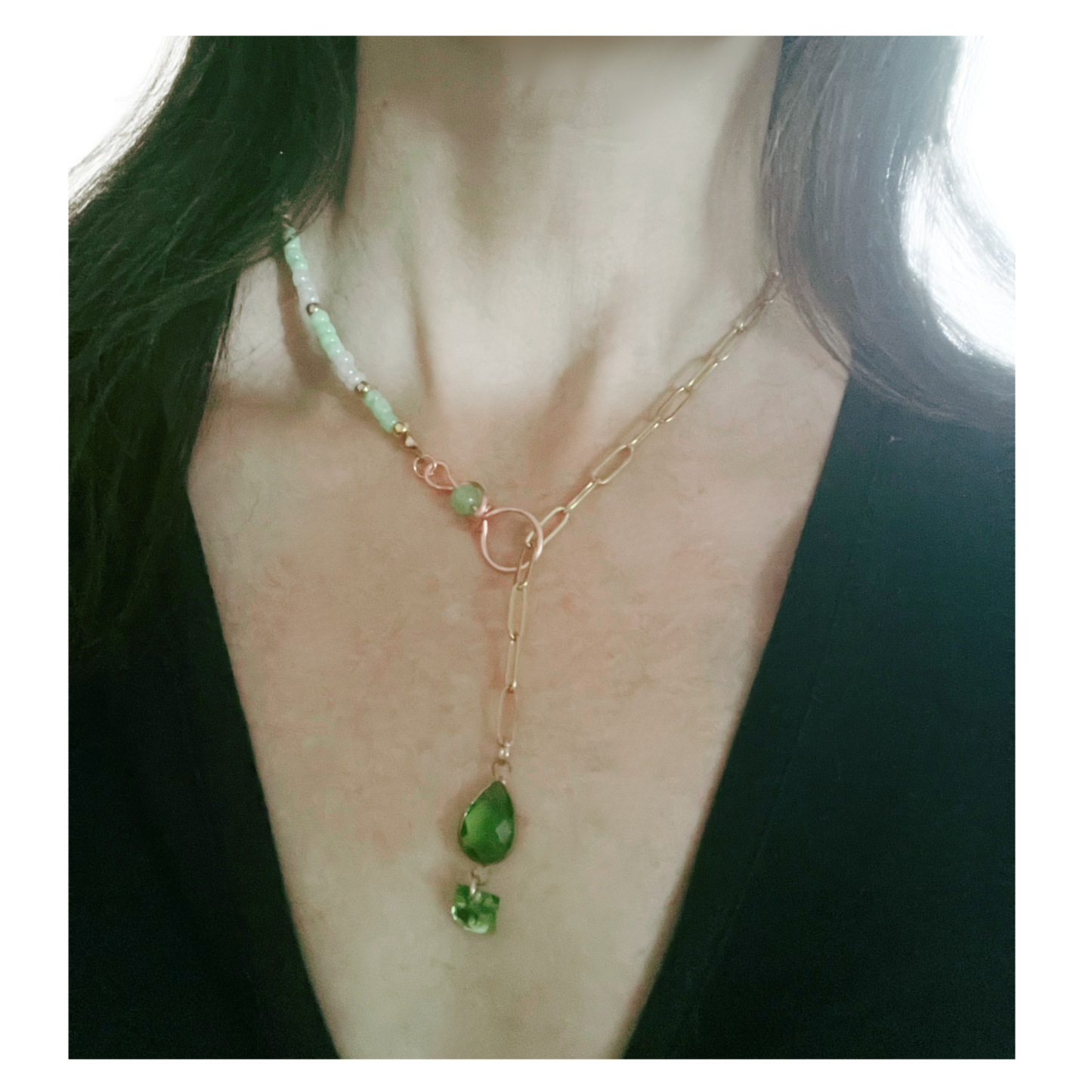 Necklace with beads and gold chain with green pendant worn.