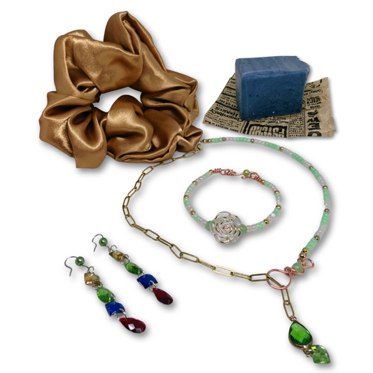 Set of jewelry including a gold satin scrunchie, necklace, bracelet, earrings  and a mint exfoliant mini soap. 