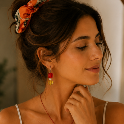 Bohemian-style red beaded necklace with a silver pendant, matching red and yellow earrings, and a red beaded bracelet, styled  an orange hair scrunchie.