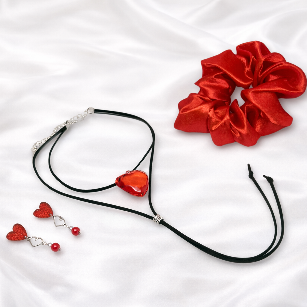 A striking trio crafted for the bold and romantic soul. This gift-ready combo includes a fiery red satin scrunchie, a layered black cord choker with a statement red heart pendant, and matching dangle earrings featuring shimmering red hearts and delicate silver accents.
