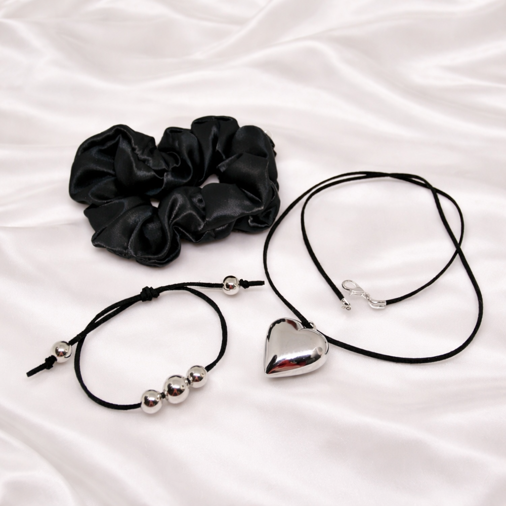 Serene Midnight Charm gift set for women, featuring black satin hair scrunchie, black suede necklace with silver heart pendant, black suede matching bracelet with silver beads and gift bag.