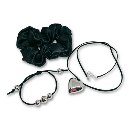 Serene Midnight Charm gift set for women, featuring black satin hair scrunchie, black suede necklace with silver heart pendant, black suede matching bracelet with silver beads and gift bag.