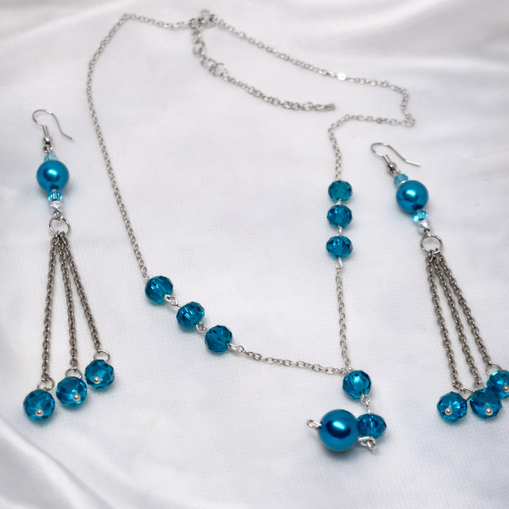 The Elegance gift set for women featuring silver necklace with blue pearls and matching earrings inside a cute organza gift bag.